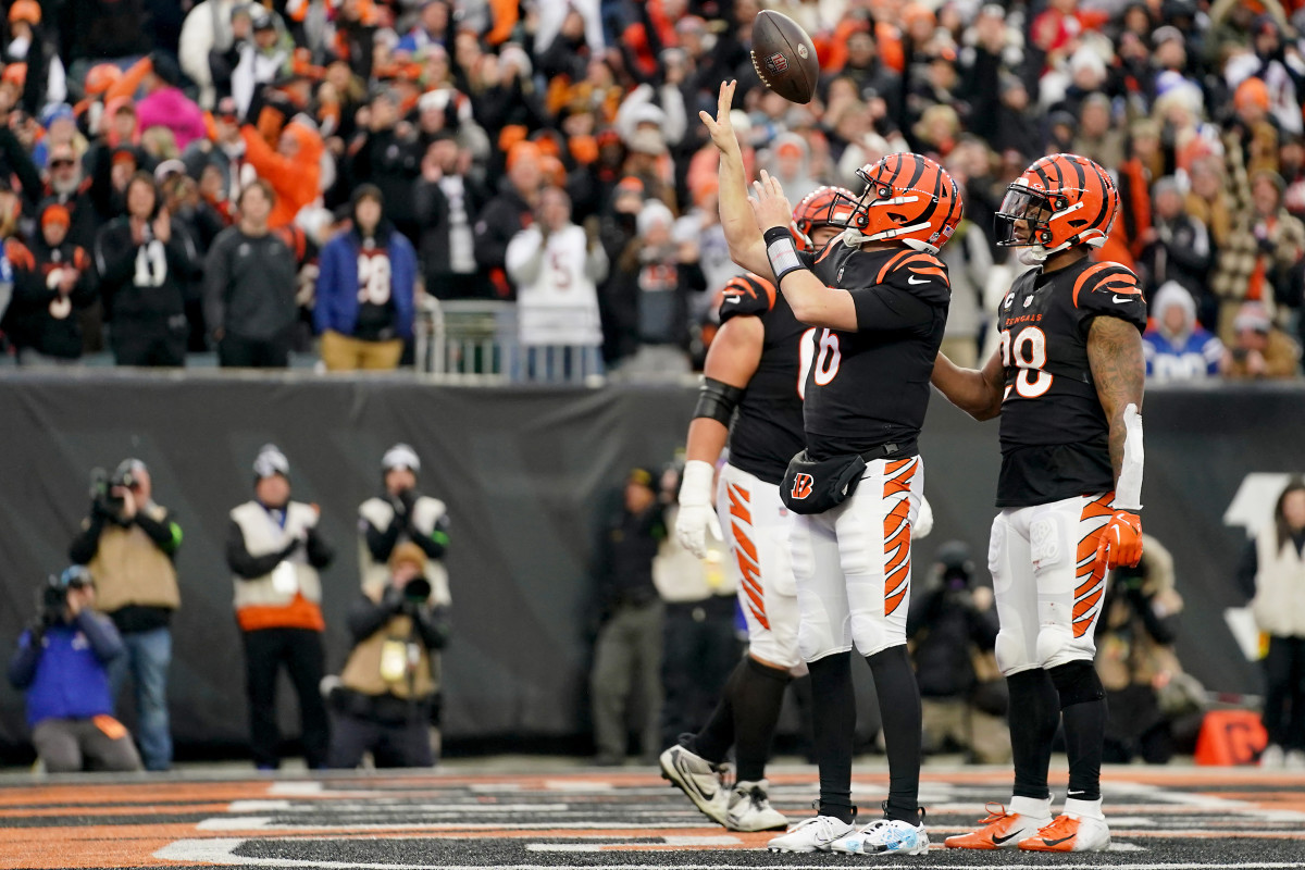 Jake Browning flicks the ball up in the air, standing in the endzone with two teammates celebrating a touchdown