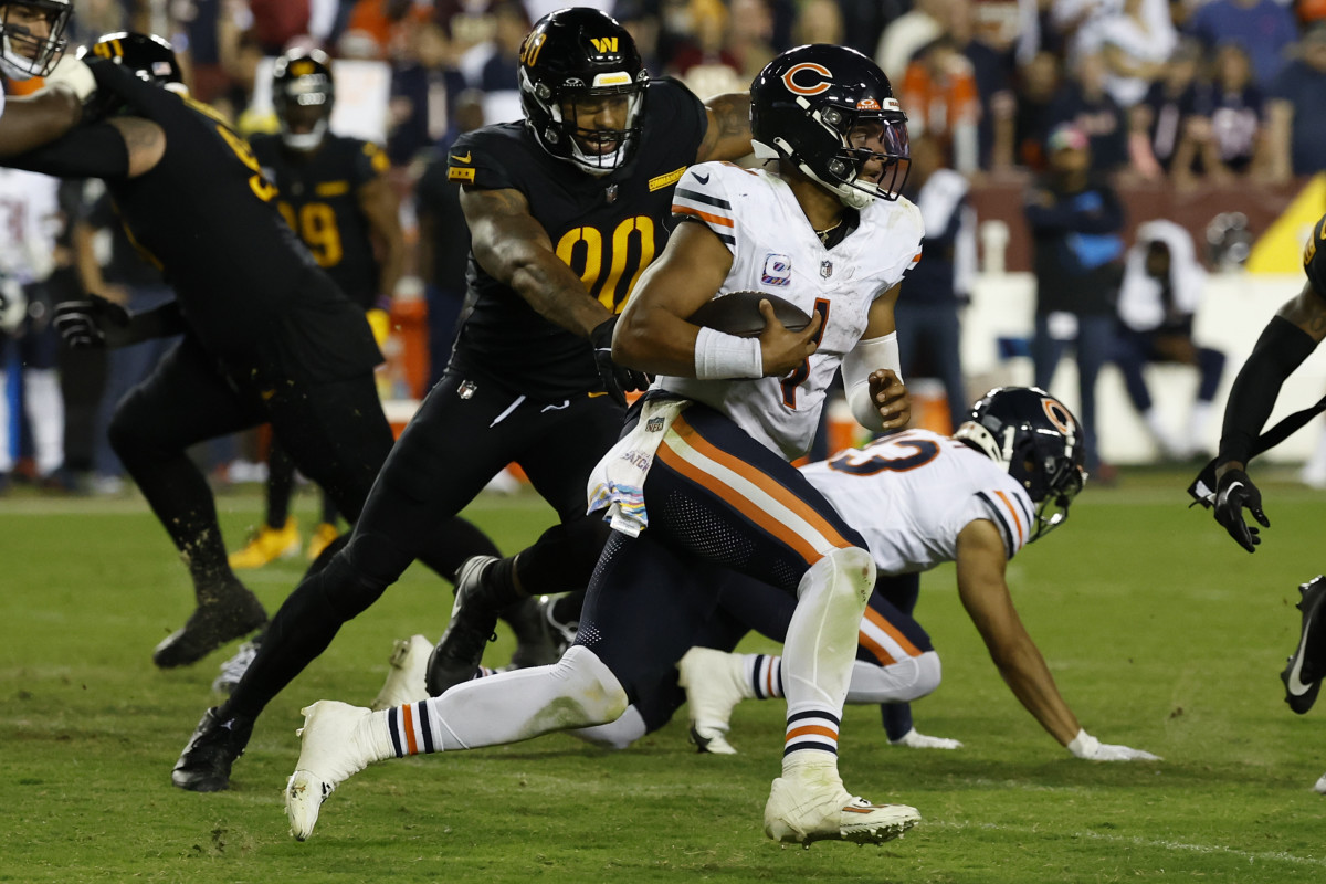Chicago Bears quarterback Justin Fields (1) runs with the ball past Washington Commanders defensive end Montez Sweat (90) during the fourth quarter at FedExField.