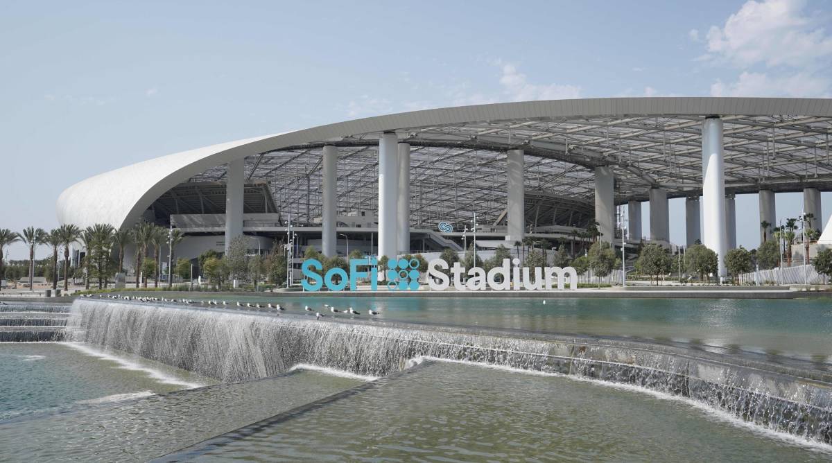 The outside of SoFi Stadium in Los Angeles next to a waterfall during the day.
