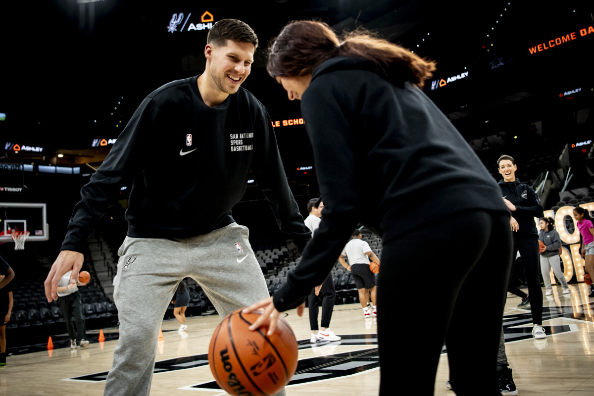 San Antonio Spurs small forward Doug McDermott defends one of the girls from S.J. Davis Middle School's girls basketball team as she practices her dribbling and passing during a rotating station.