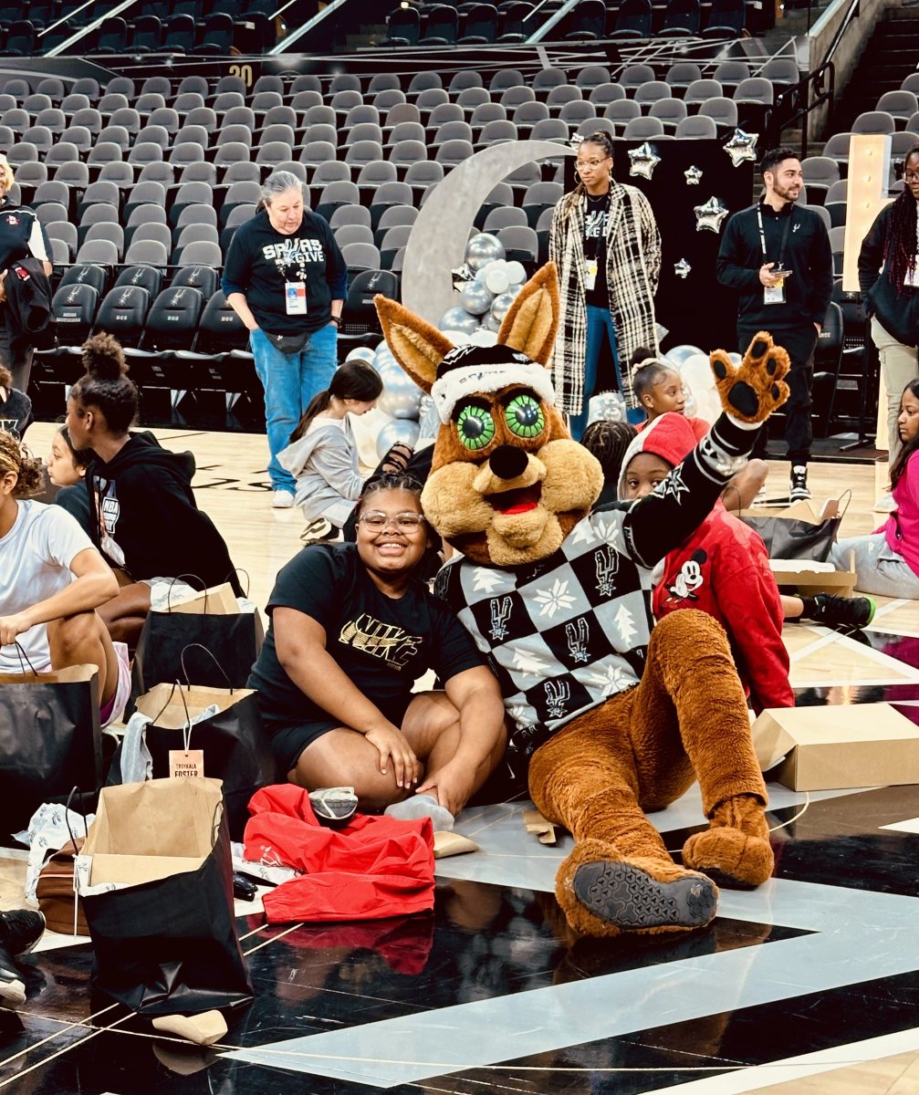 The San Antonio Spurs' Coyote poses for a photo with one of the girls from S.J. Davis Middle School following the team's gift-opening at Frost Bank Center.