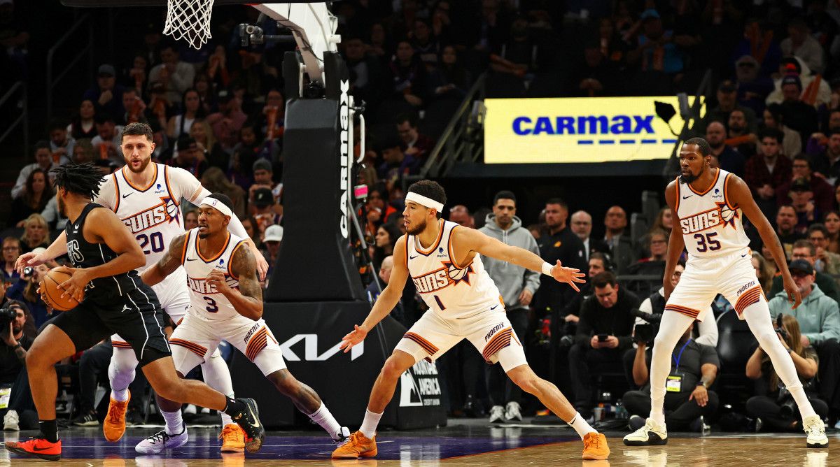 Bradley Beal defends a player with the ball as Devin Booker and Kevin Durant prepare to crash next to him