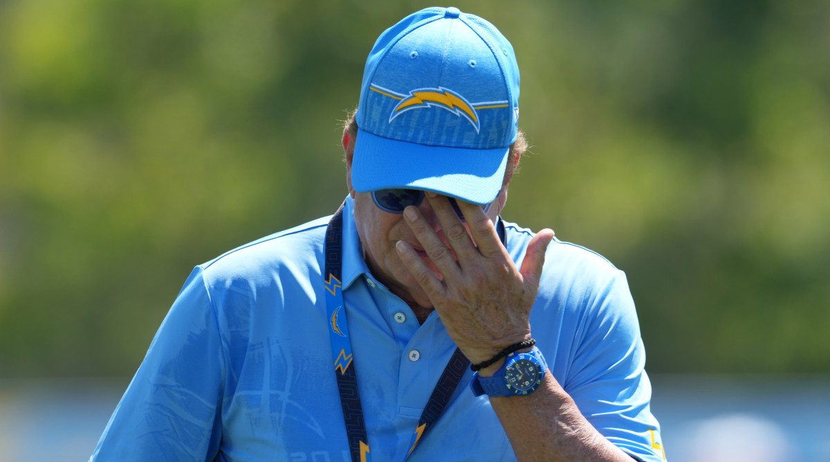Chargers owner Dean Spanos reacts by putting his hand up to his face during training camp practice.