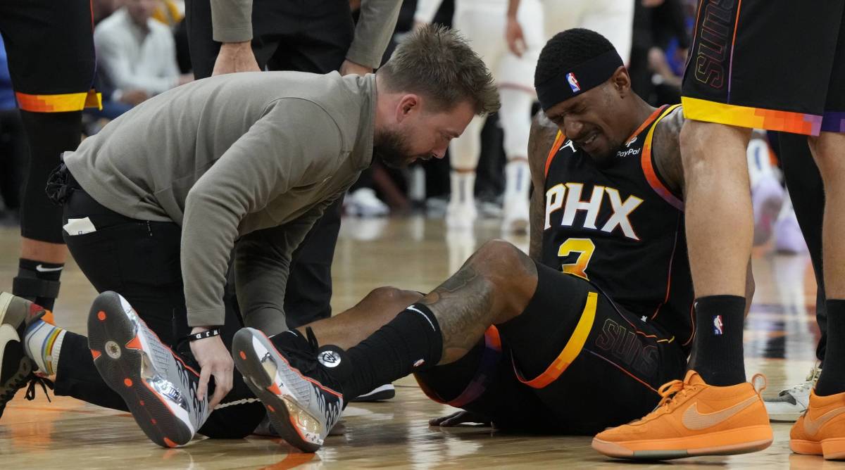 Suns guard Bradley gets looked at by trainers after spraining his right ankle in a game.