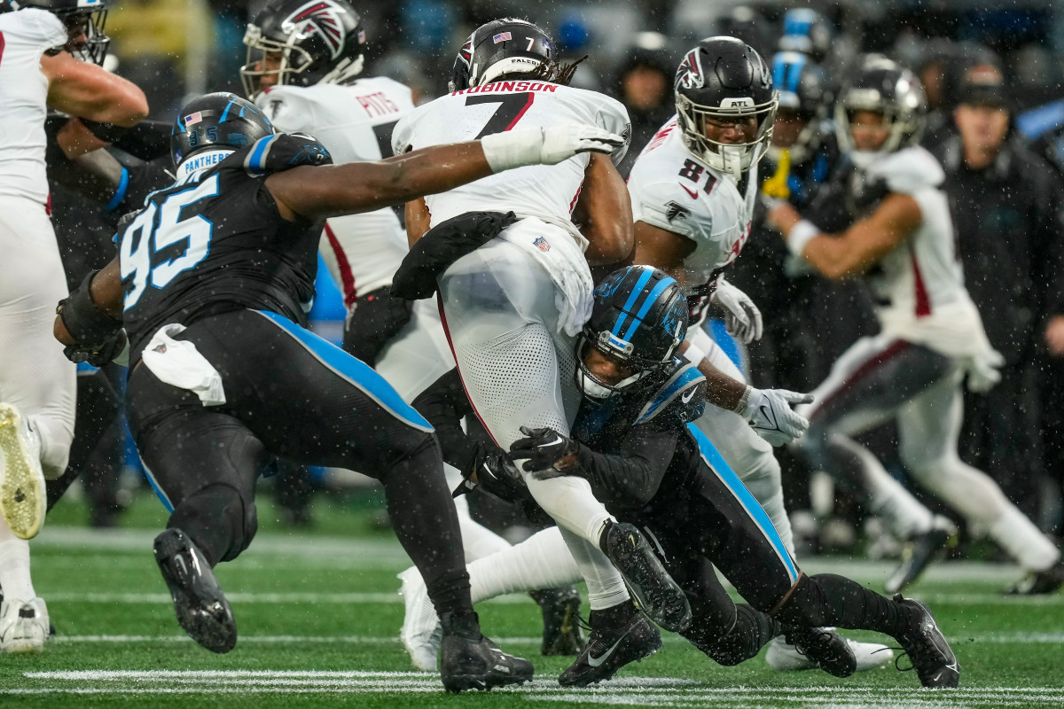 Atlanta Falcons running back Bijan Robinson (7) is tackled by Carolina Panthers defensive tackle Derrick Brown (95) and cornerback Troy Hill (13) during the second half at Bank of America Stadium.