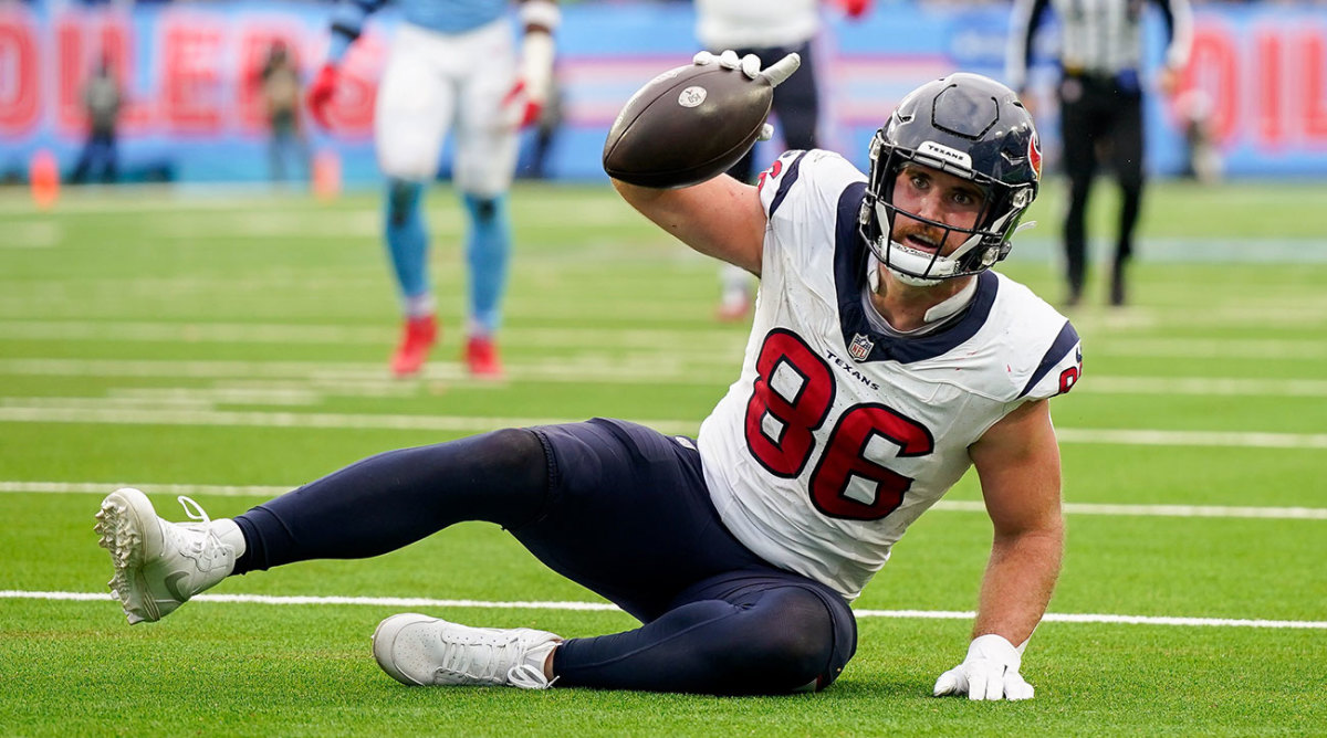 Dalton Schultz celebrates receiving a pass against the Titans, holding the ball up from the ground