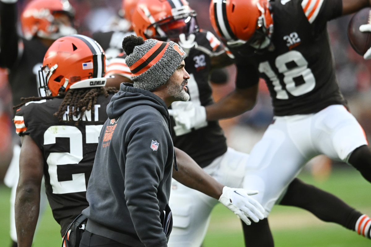 Kevin Stefanski walks as Browns players jump up behind him