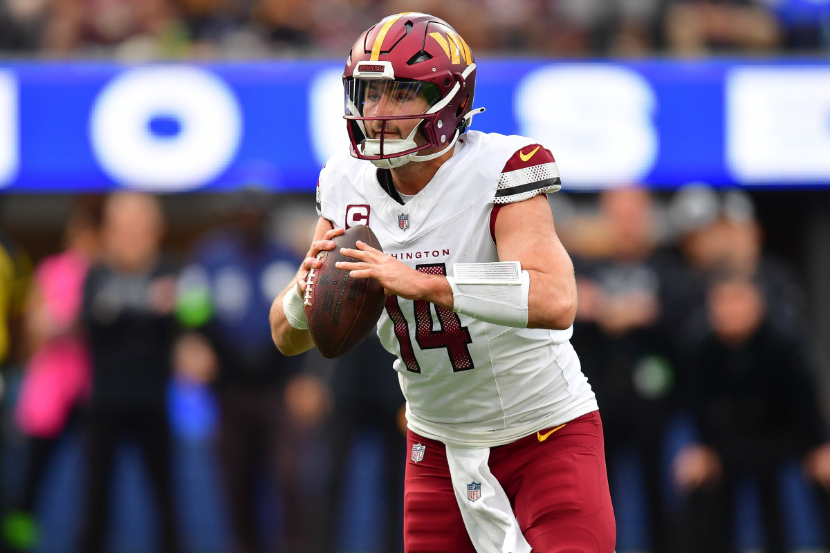 Washington Commanders quarterback Sam Howell (14) moves out to pass against the Los Angeles Rams during the first half at SoFi Stadium.