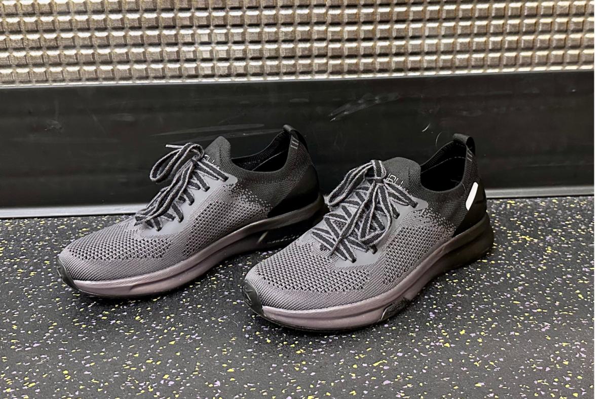 Grey and black Kuru flux shoes on black speckled gym flooring
