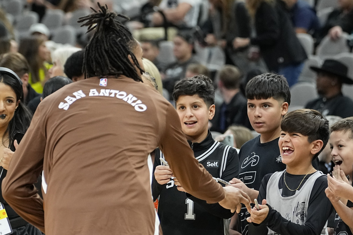 Dec 15, 2023; San Antonio, Texas, USA; San Antonio Spurs fan reacts when greeted by guard Devin Vassell (24) before a game against the Los Angeles Lakers at Frost Bank Center.