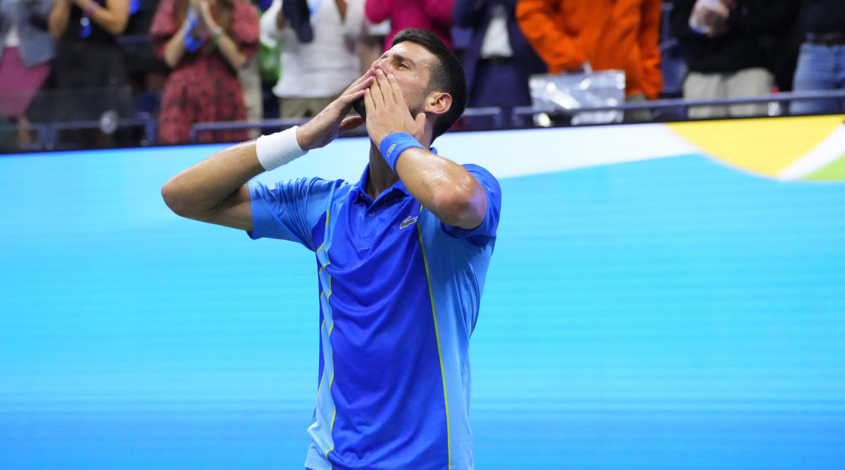 Novak Djokovic puts two hands to his mouth to blow a kiss to the audience