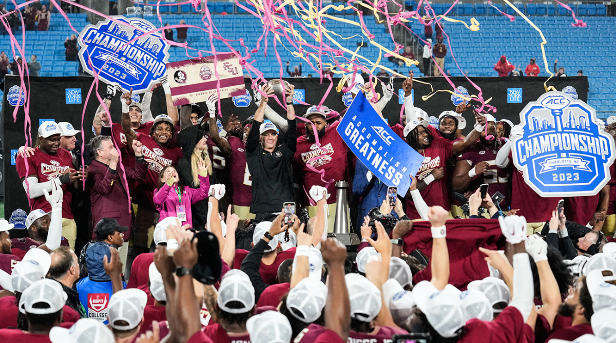 Florida State coach Mike Norvell celebrates winning the ACC Championship trophy with his players after the game against Louisville at Bank of America Stadium.
