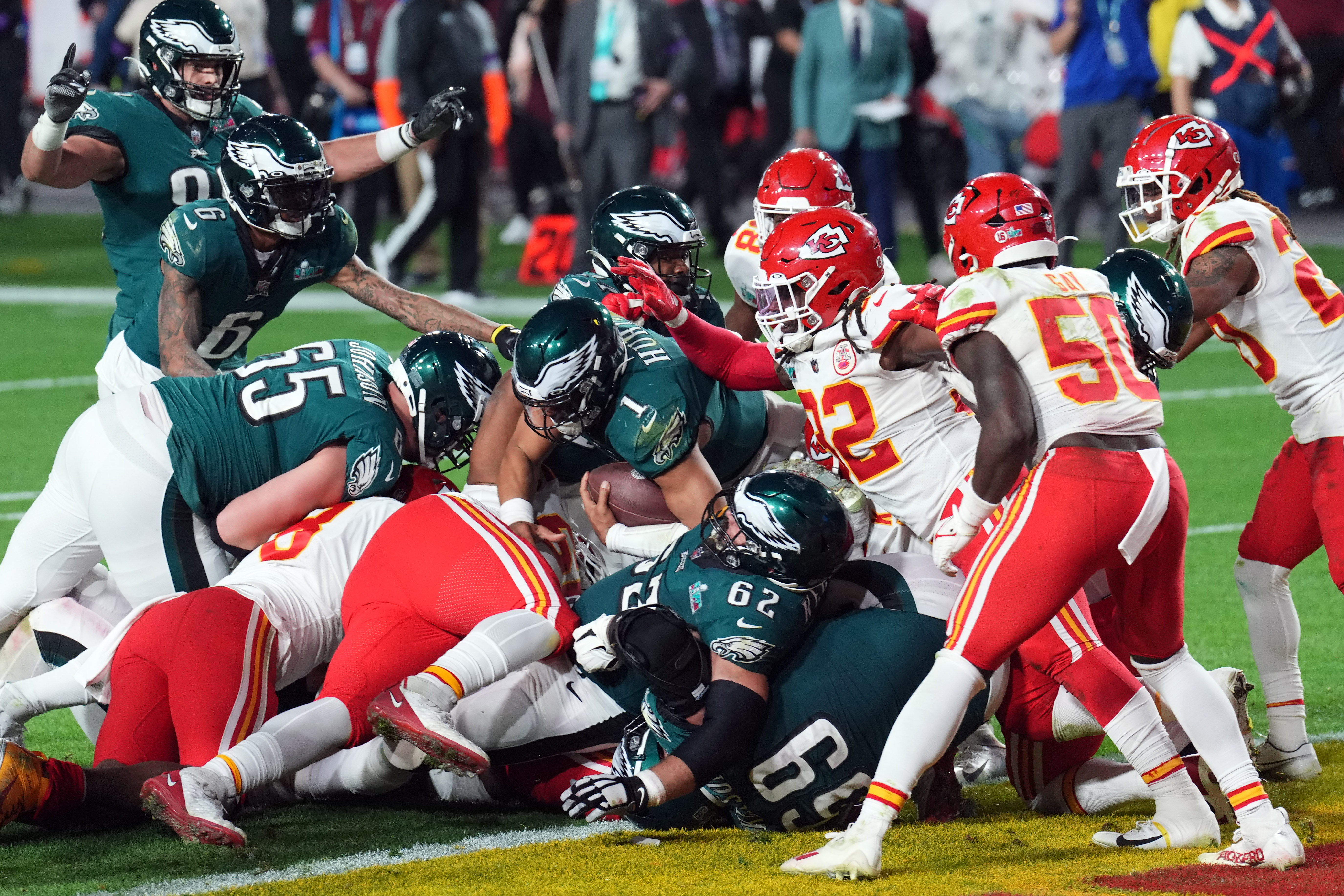 Jalen Hurts shoves himself on top of other Eagles players, while jason kelce lies on the ground and chiefs players rush to stop them