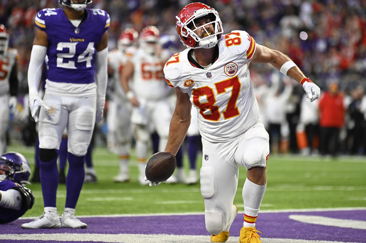 Travis Kelce kneels down with the ball in one hand celebrating a TD in the end zone
