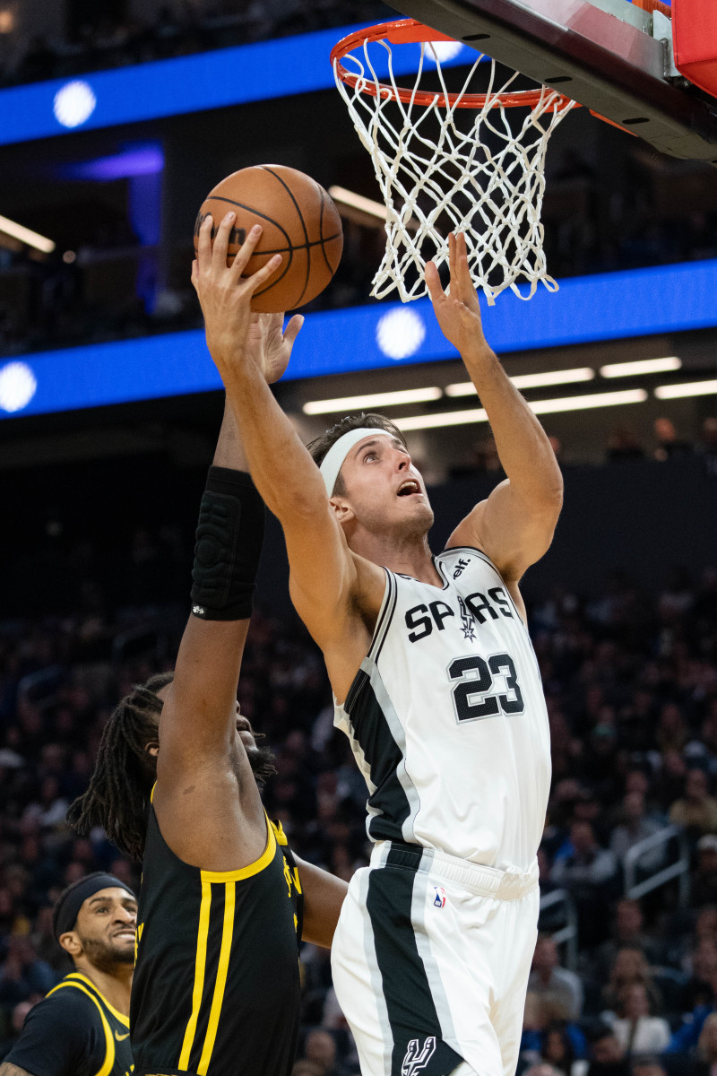 November 24, 2023; San Francisco, California, USA; San Antonio Spurs forward Zach Collins (23) shoots the basketball against Golden State Warriors forward Kevon Looney (5) during the second quarter at Chase Center.