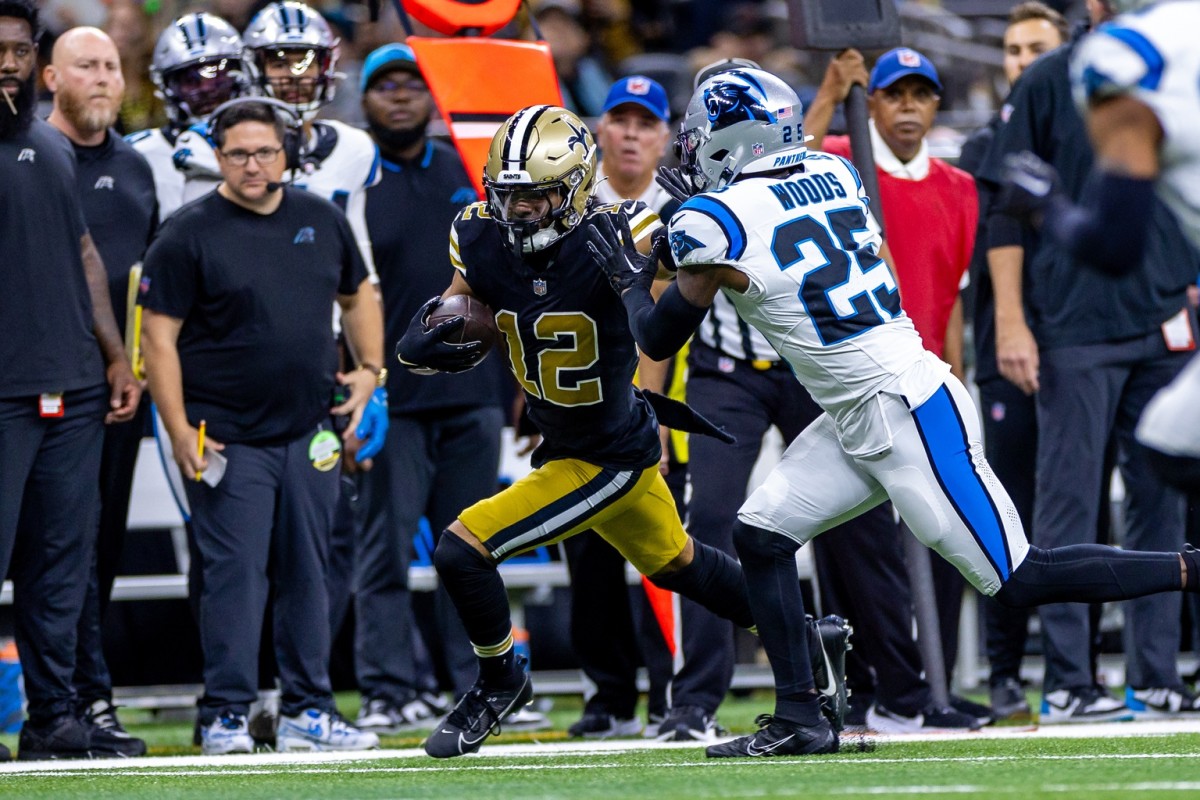 Carolina Panthers safety Xavier Woods (25) tries to tackle New Orleans Saints receiver Chris Olave (12) after a reception. Mandatory Credit: Stephen Lew-USA TODAY Sports