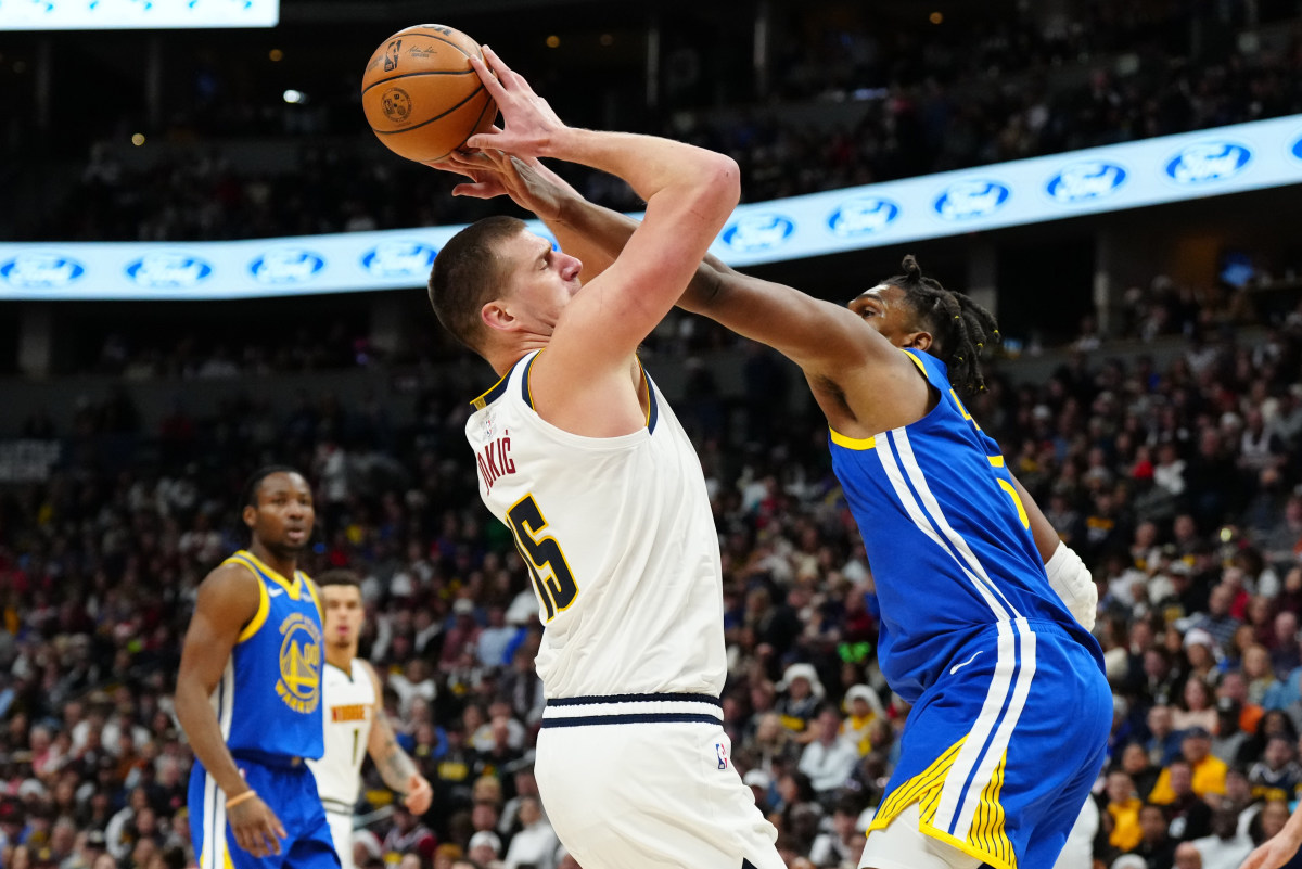 Nikola Jokic goes to shoot the basketball as Kevon Looney reaches and fouls him