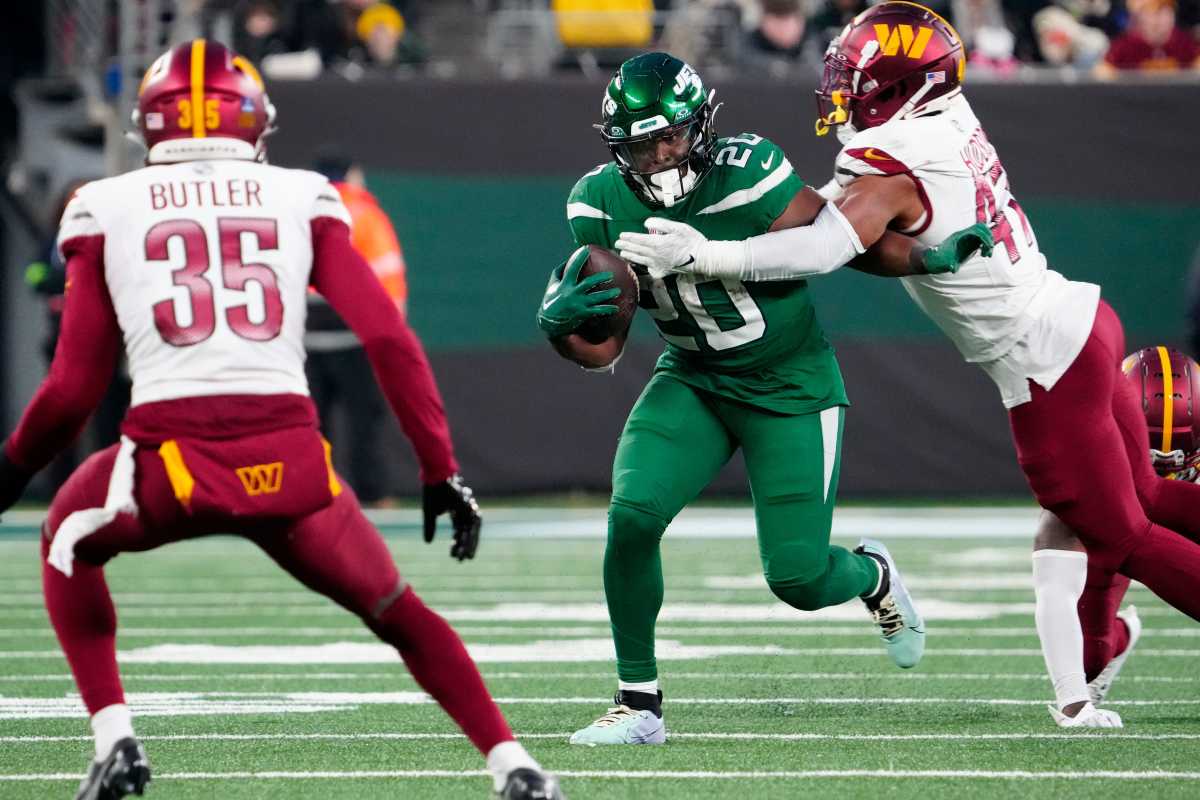 Breece Hall runs with the ball as Commanders defenders try to tackle him