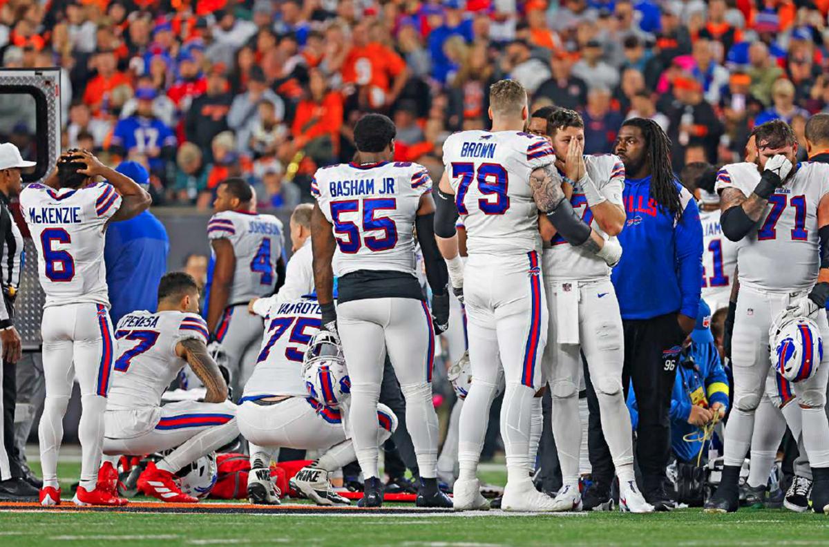 Bills players gather in a group with shocked, distressed looks on their faces