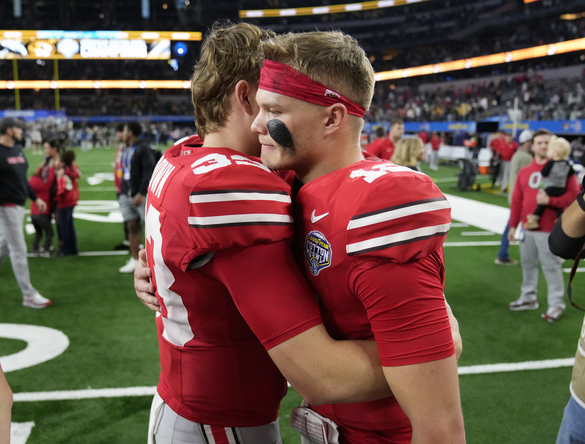 Dec 29, 2023; Arlington, TX, USA; Ohio State Buckeyes quarterback Devin Brown (33) hugs Ohio State Buckeyes quarterback Lincoln Kienholz (12) after losing 14-3 to Missouri Tigers in the Goodyear Cotton Bowl Classic at AT&T Stadium. 