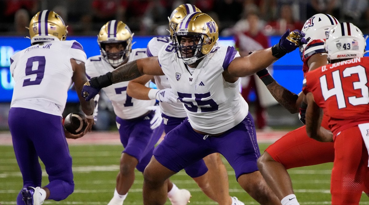 Washington offensive lineman Troy Fautanu (55) blocks for running back Dillon Johnson (7) who takes a handoff from quarterback Michael Penix Jr. (9) during a game against Arizona.