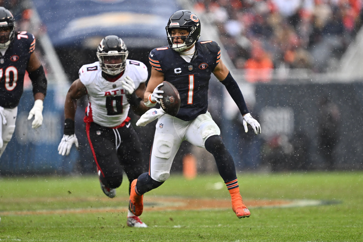 Dec 31, 2023; Chicago, Illinois, USA; Chicago Bears quarterback Justin Fields (1) scrambles away from outside linebacker Lorenzo Carter (0) for yards in the first half against the Atlanta Falcons at Soldier Field.