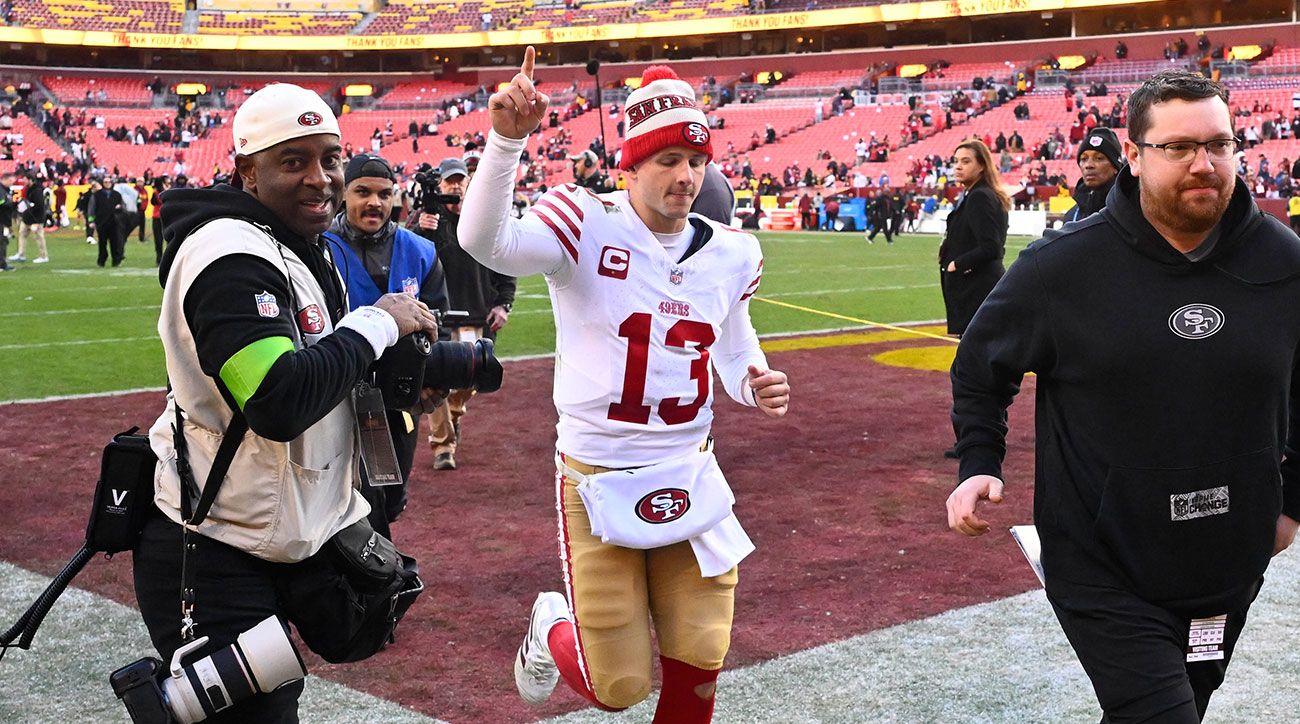 Brock Purdy runs off the field holding up a finger to show the 49ers are No. 1