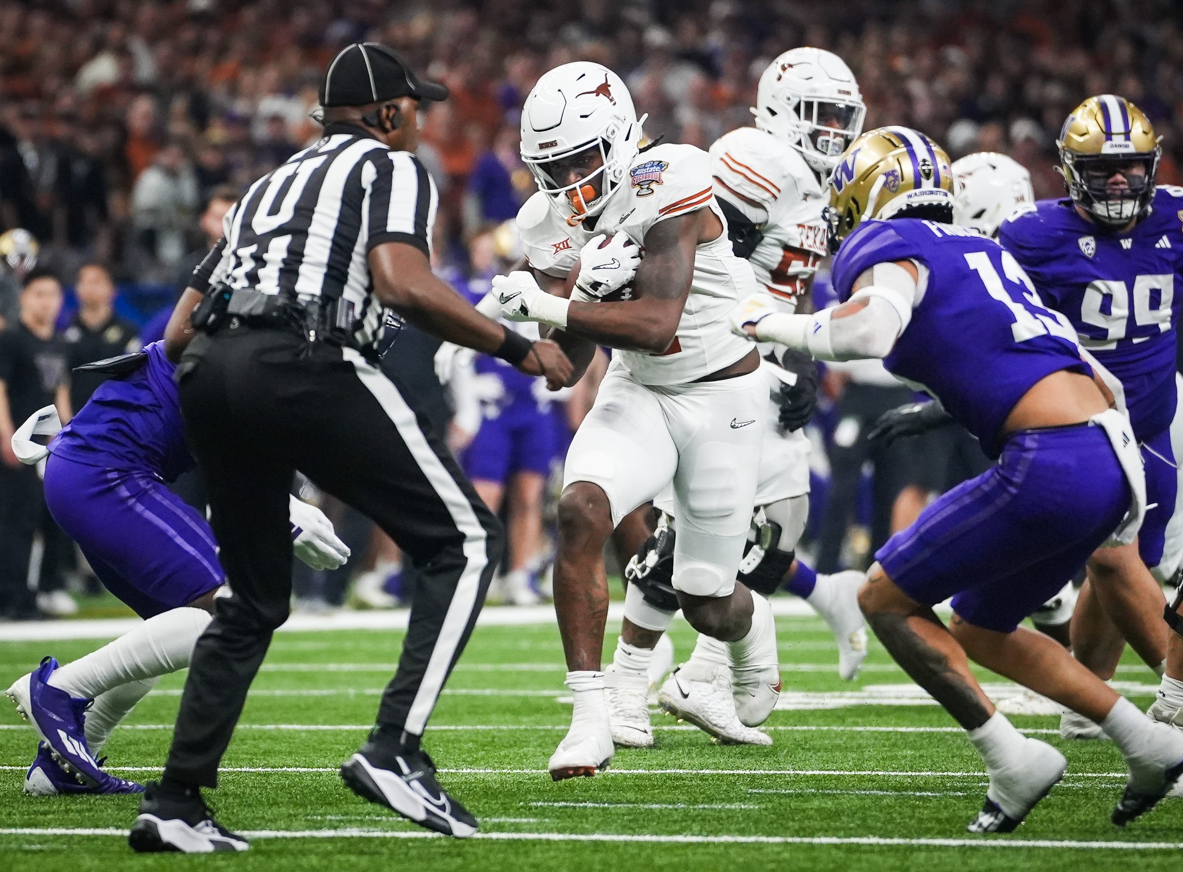 Texas Longhorns running back CJ Baxter (4) carries the ball through the Washington Huskies defense in the second quarter of the Sugar Bowl College Football Playoff semi-finals at the Ceasars Superdome in New Orleans, Louisiana, Jan. 1, 2024. The Texas Longhorns take on the Washington Huskies for a spot in the College Football Playoff Finals.