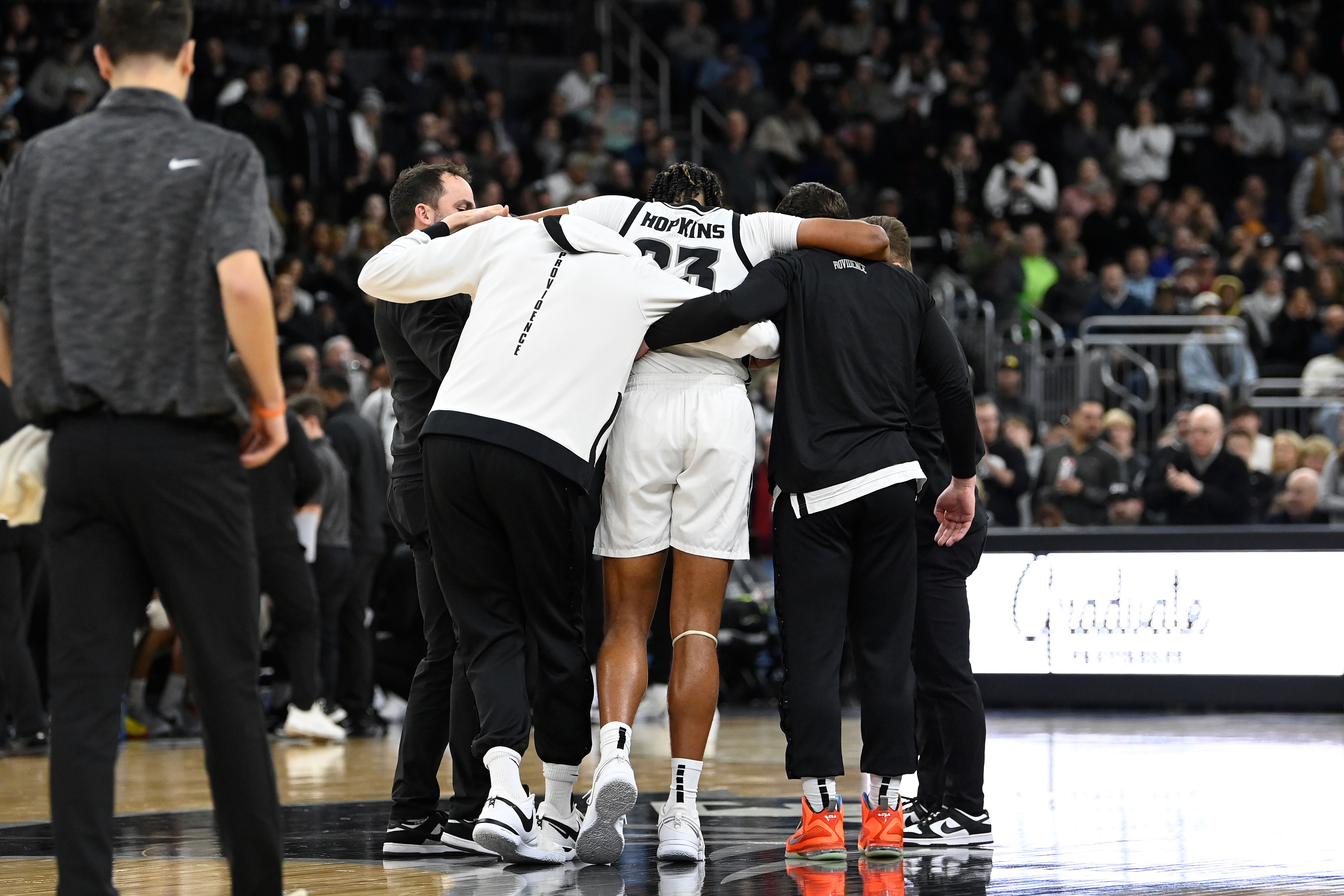 Bryce Hopkins is helped off the court with his arms around two people on each side of him