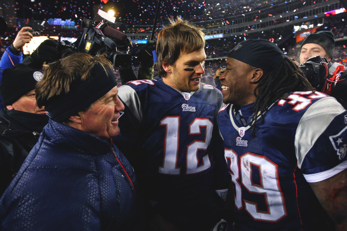 Bill Belichick talks to Tom Brady and Laurence Maroney as people around them film and celebrate