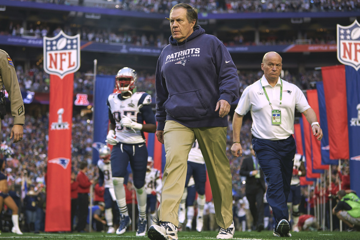 Bill Belichick walks onto the field at Super Bowl XLIX as Patriots staff and players run out behind him