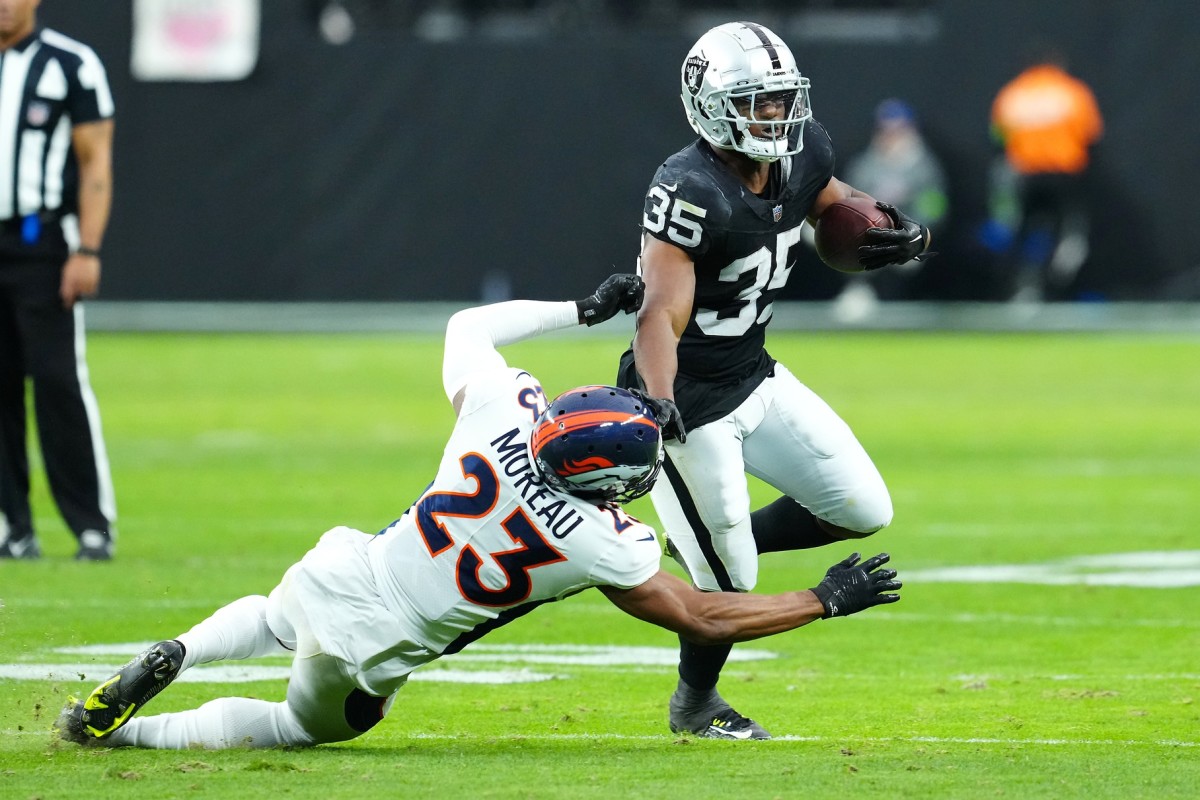 Las Vegas Raiders running back Zamir White (35) breaks the tackle of Denver Broncos cornerback Fabian Moreau (23) during the second quarter at Allegiant Stadium.