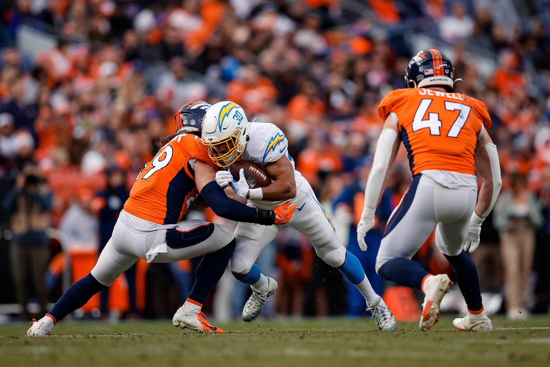 Los Angeles Chargers running back Austin Ekeler (30) is tackled by Denver Broncos linebacker Alex Singleton (49) as linebacker Josey Jewell (47) defends in the second quarter at Empower Field at Mile High.