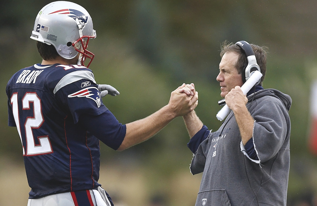 Bill Belichick clasps hands with Tom Brady.