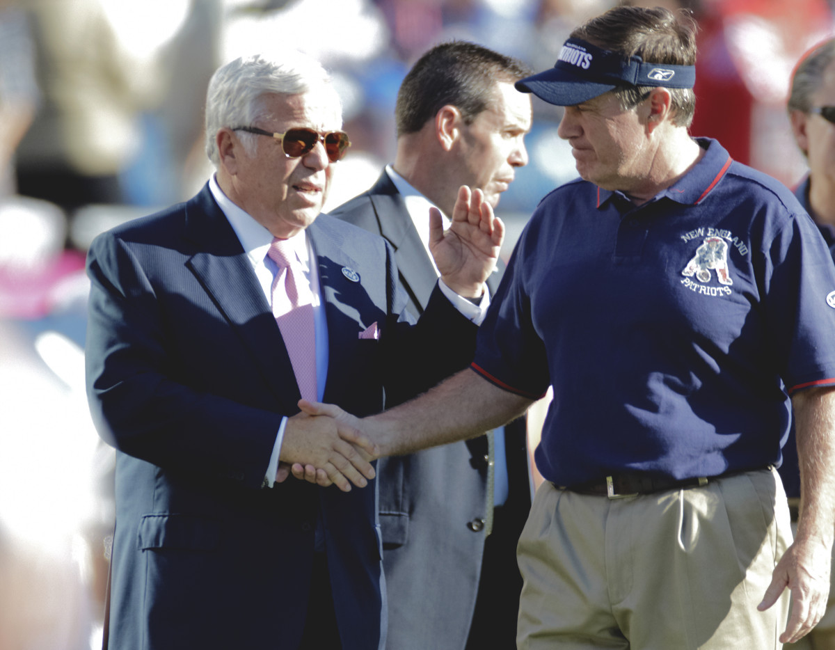 Robert Kraft shakes hands with Bill Belichick on the field.