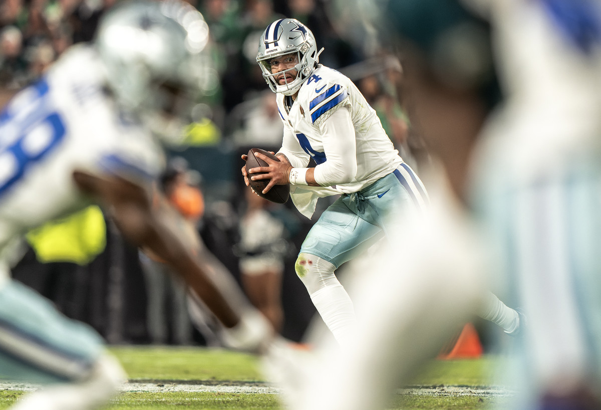 Dak Prescott runs with the ball in between his two hands