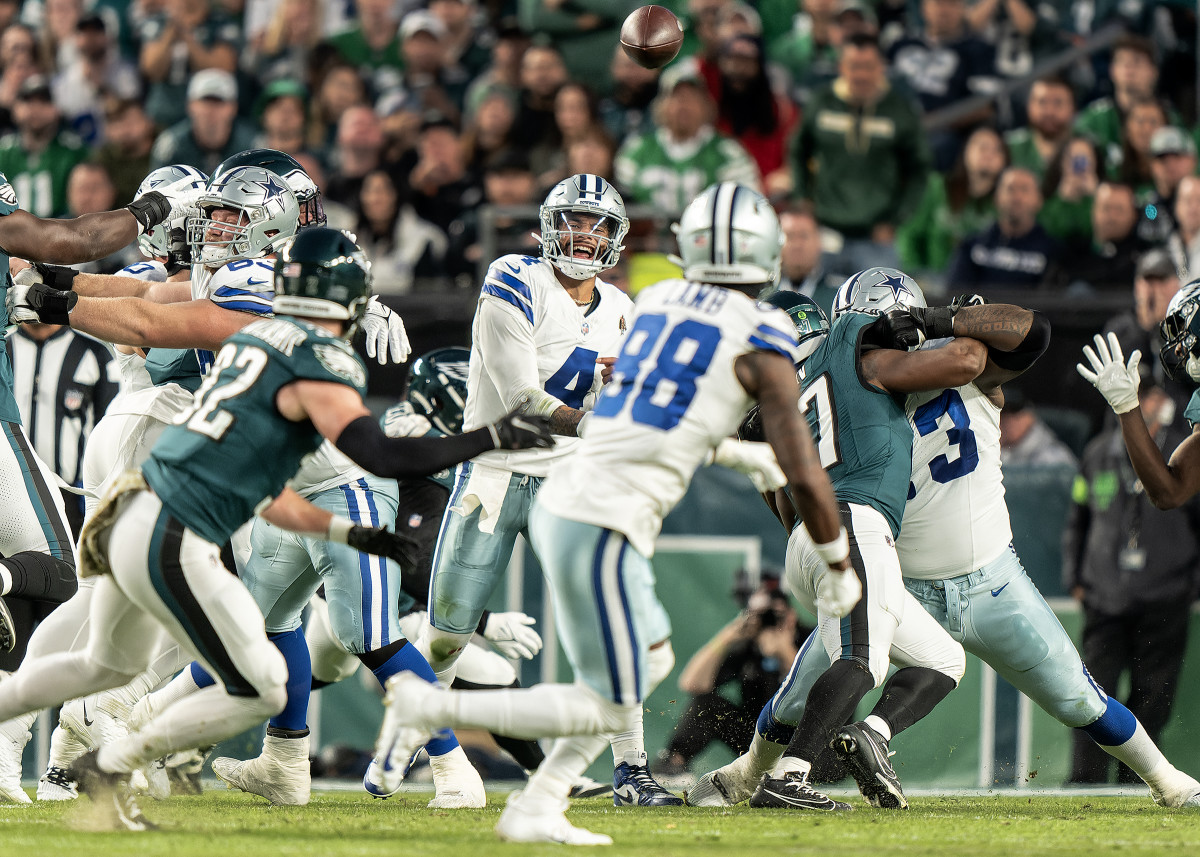 Dak Prescott yells as he looks to CeeDee Lamb and Eagles players swarm him