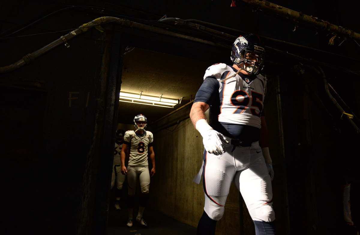 Derek Wolfe walks out of a dark tunnel onto the field.