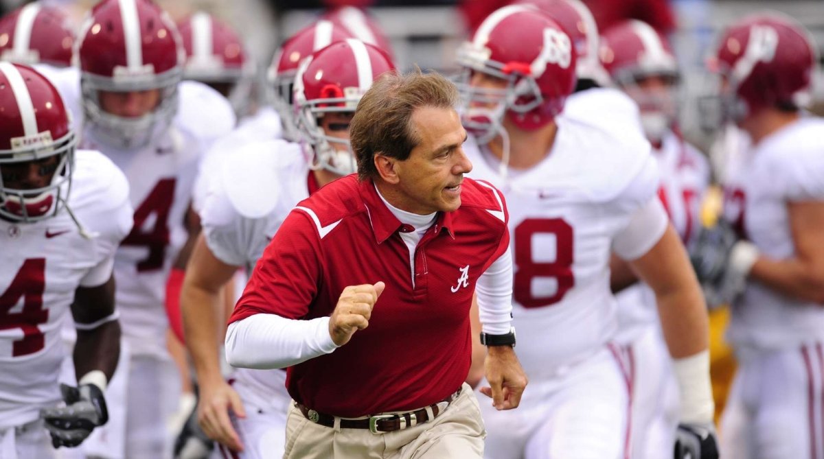 Alabama coach Nick Saban runs out onto the field with the Crimson Tide trailing behind him.