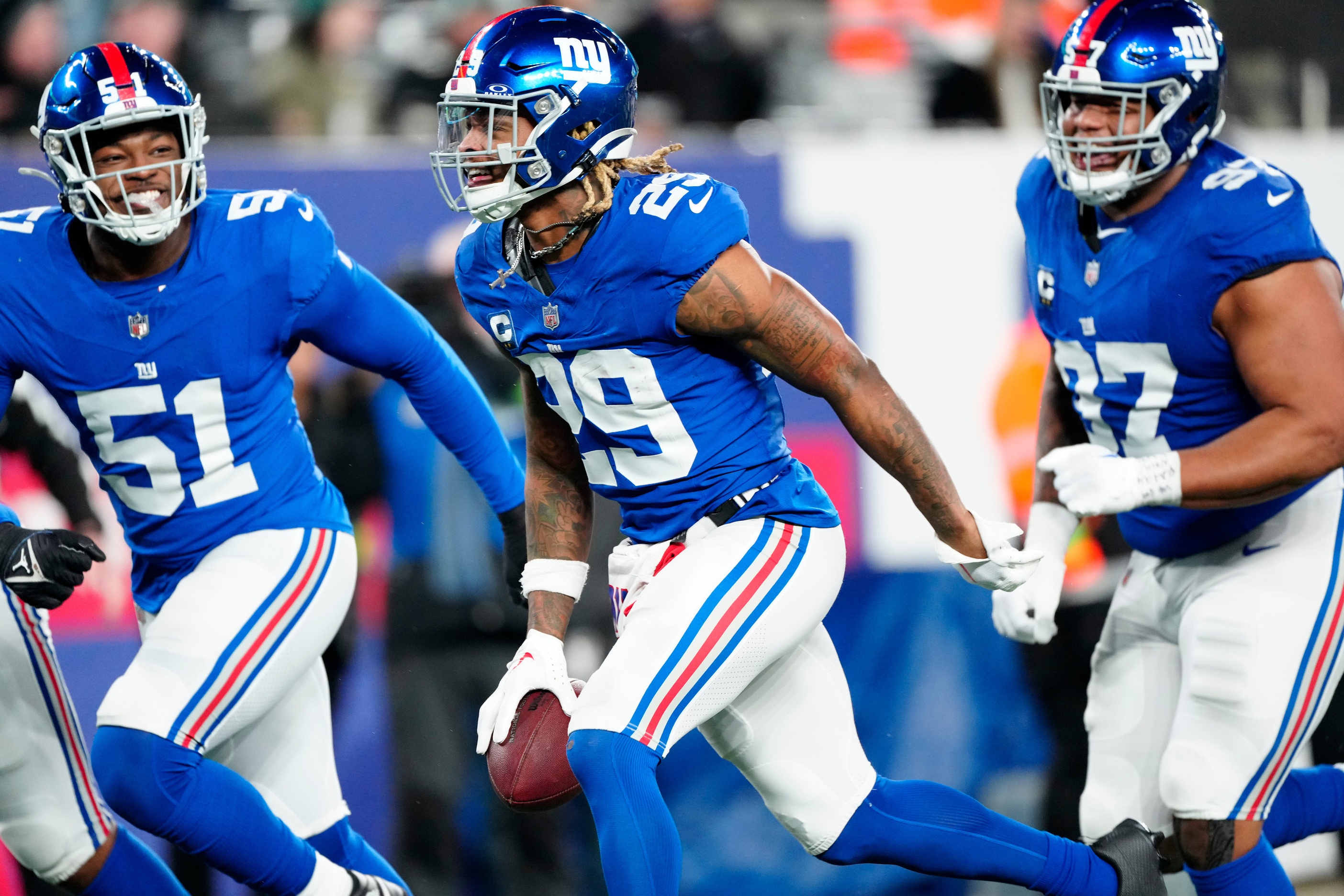 New York Giants safety Xavier McKinney (29) holds the ball as he celebrates with New York Giants linebacker Azeez Ojulari (51) and New York Giants defensive tackle Dexter Lawrence II (97) after he intercepted a Philadelphia Eagles pass on Sunday, January 7, 2024.
