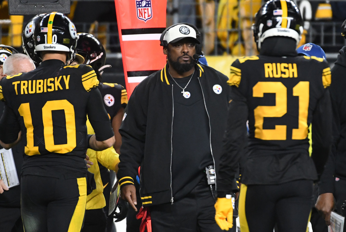 Mike Tomlin walks forward while Mitchell Trubisky and Darius Rush walk the other way on either side of the coach