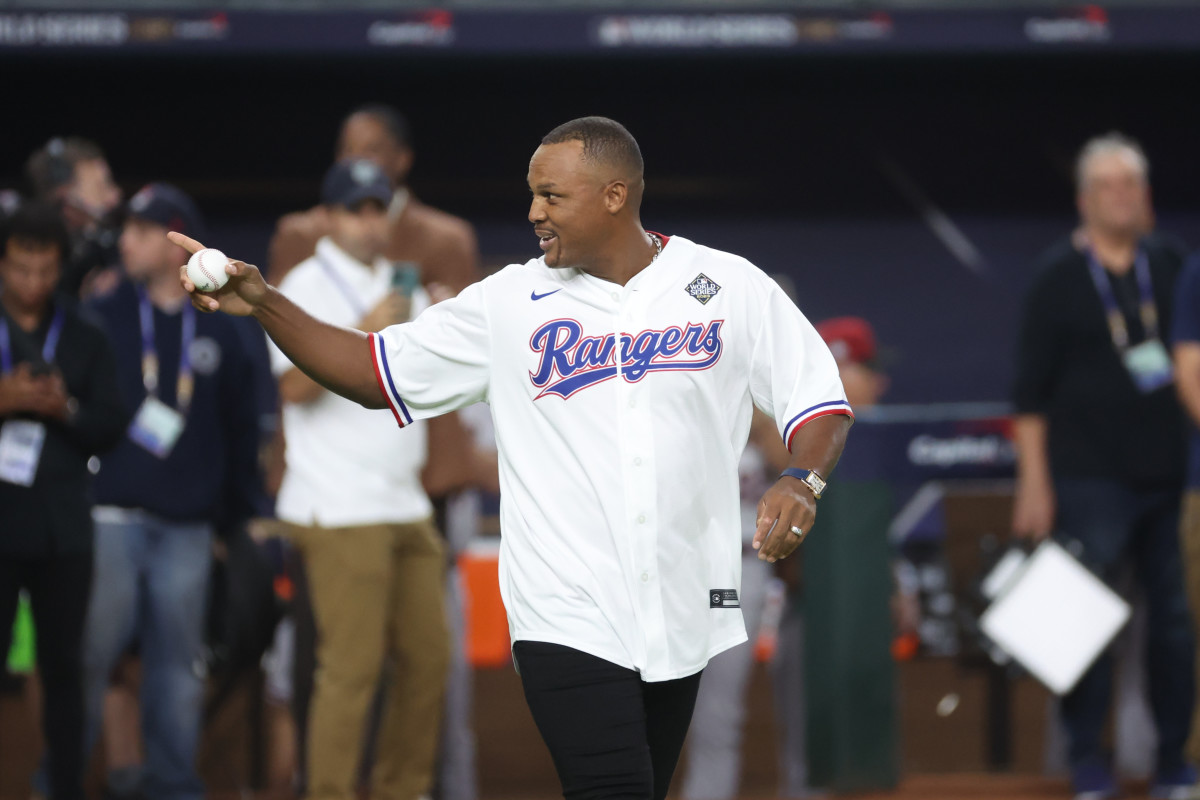 Adrián Beltré points to the side holding a baseball and smiling