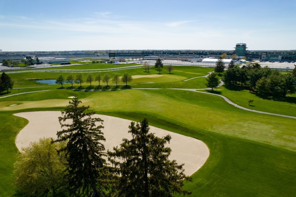 The 10th hole is shown in foreground, while the par-3 seventh green is in the background, separated by a row of trees. In the distance are Indianapolis Motor Speedway's famed pagoda and Turn One.