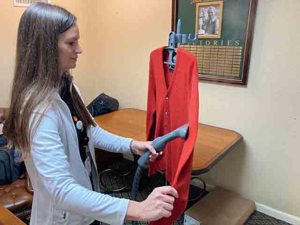 Leslie Glover, marketing manager for Bay Hill Club's golf shop, steams a red cardigan sweater.