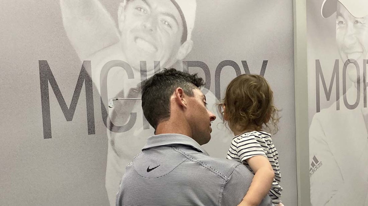 Rory McIlroy and his daughter look at his mural in the media center at the 2022 PGA Championship.