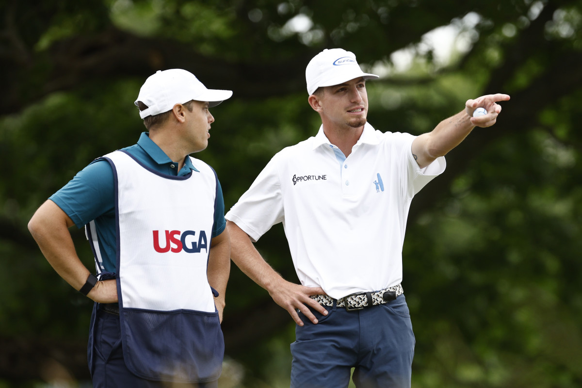 Amateur Sam Bennett (R) of the United States and caddie Taylor Ford (L) talk on the sixth tee during round one of the 122nd U.S. Open Championship at The Country Club.