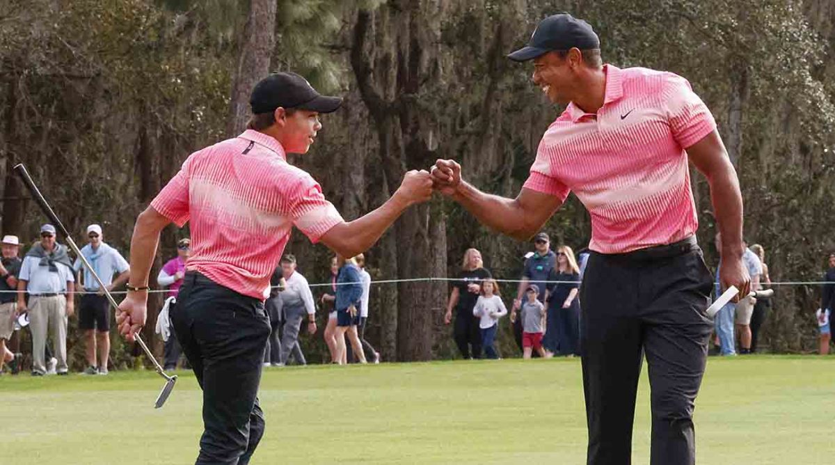 Charlie Woods and father Tiger Woods fist bump after a birdie on the ninth hole during the first round of the 2022 PNC Championship at Ritz Carlton Golf Club in Orlando, Fla.