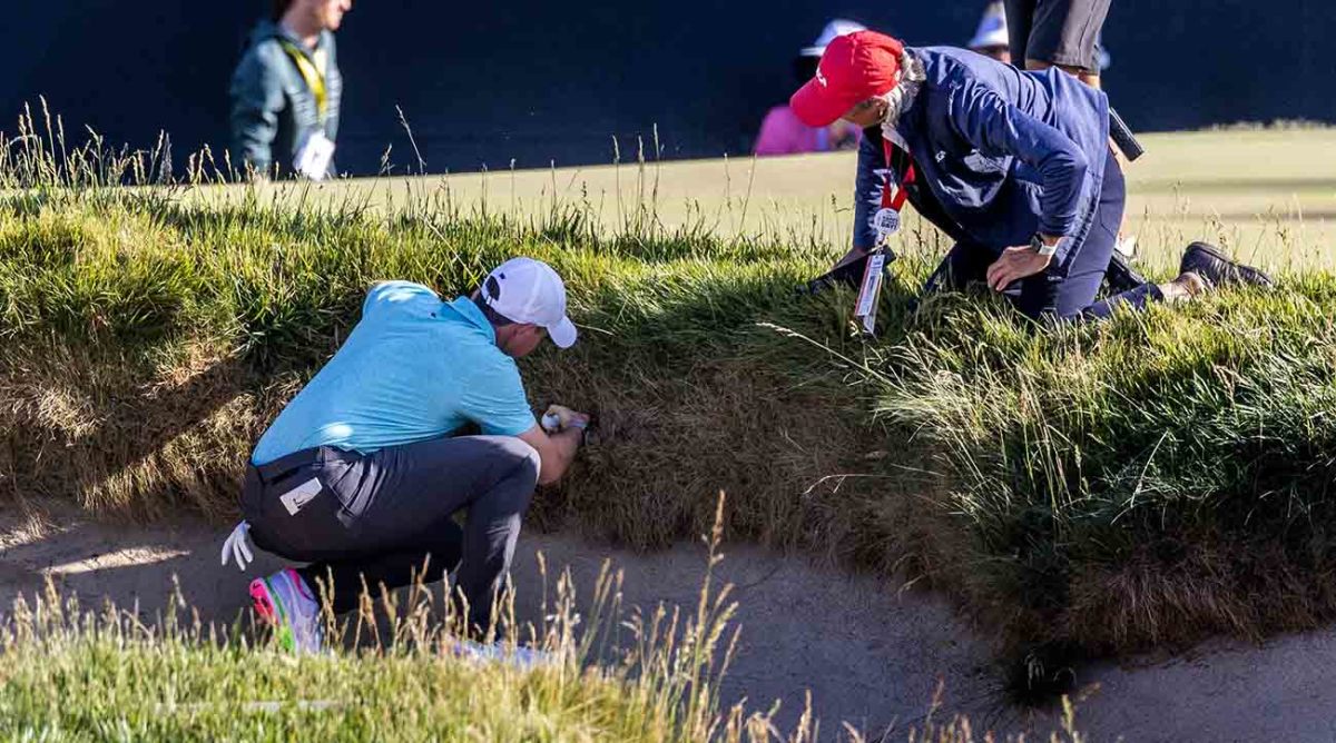 Rory McIlroy and a USGA rules official examine an embedded ball situation at the 2023 U.S. Open.