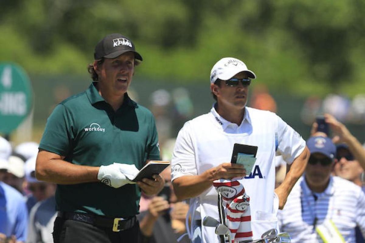 Phil Mickelson (left), with his brother/caddie Tim, incurs a two-stroke penalty for hitting a moving ball, but it should have been worse.