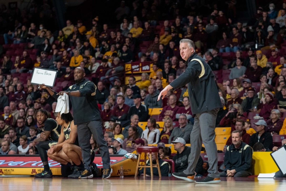 Terry Johnson holds up a whiteboard with a play call while Painter signals to players during a game last season.